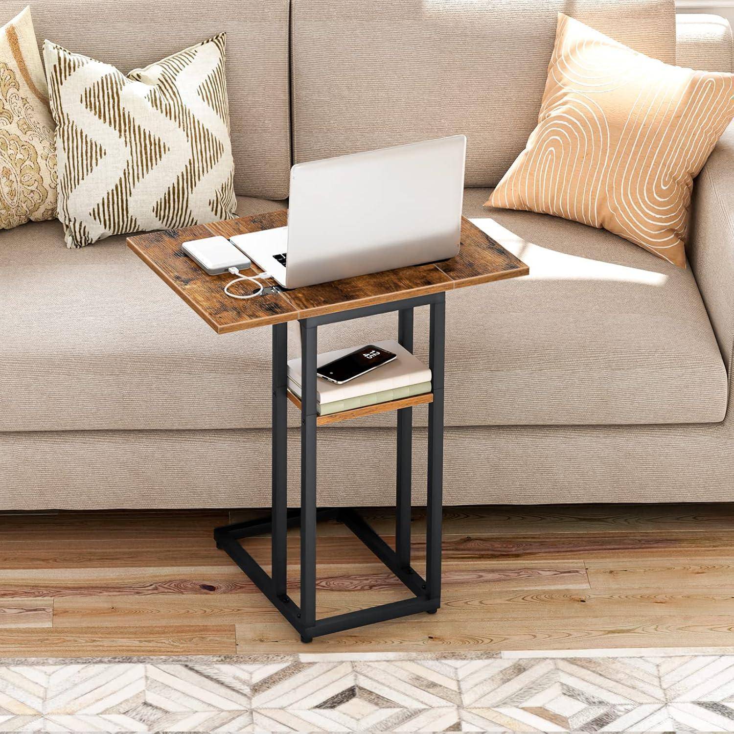 Ein kleiner Laptoptisch mit einer Holzplatte und einem schwarzen Metallgestell steht neben einem beigen Sofa. Darauf befinden sich ein Laptop, ein Notizbuch und ein Untersetzer.