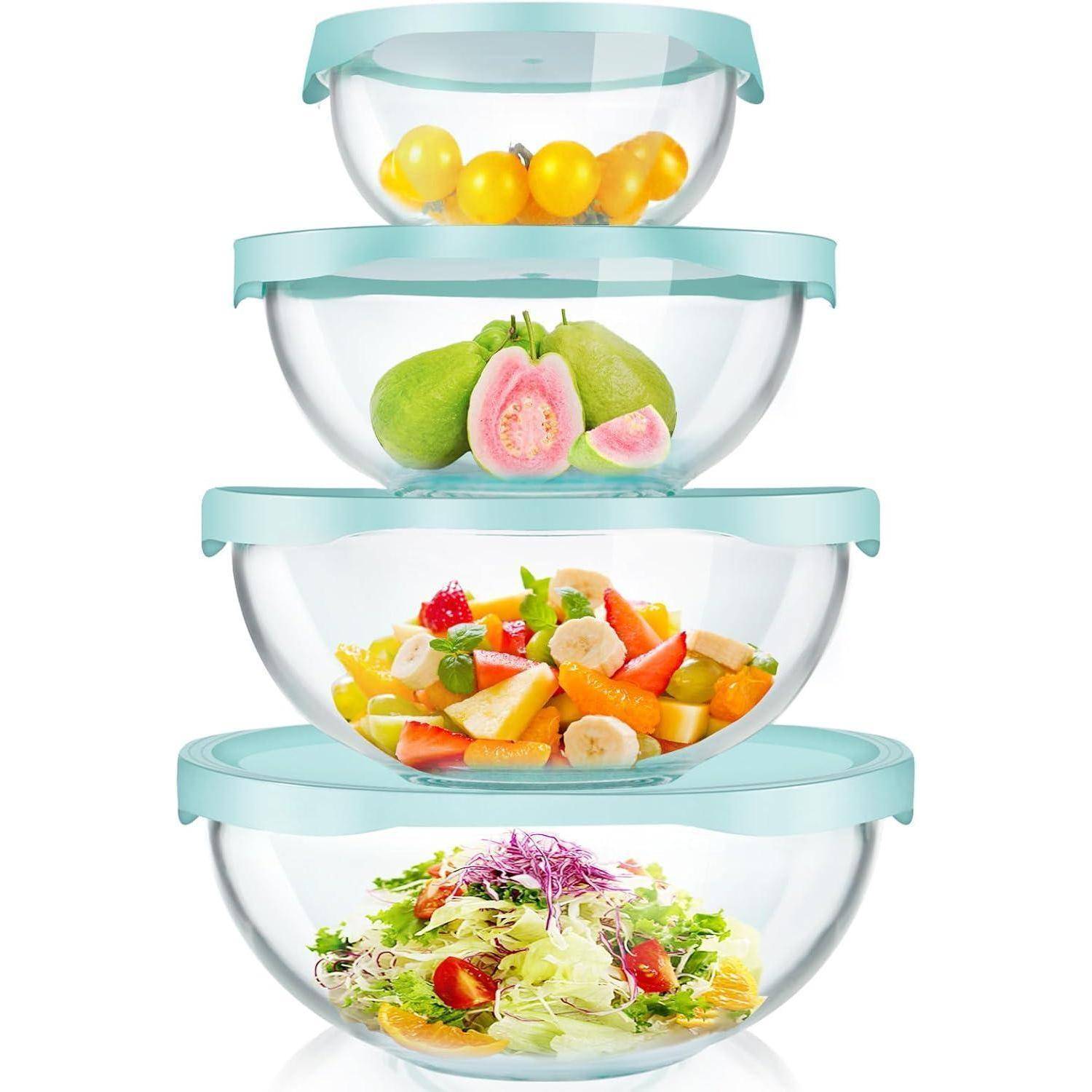 Vier transparente Schüsseln mit blauen Deckeln, die jeweils verschiedene Lebensmittel enthalten: gelbe Tomaten, Guaven, gemischten Obstsalat und Blattsalat.