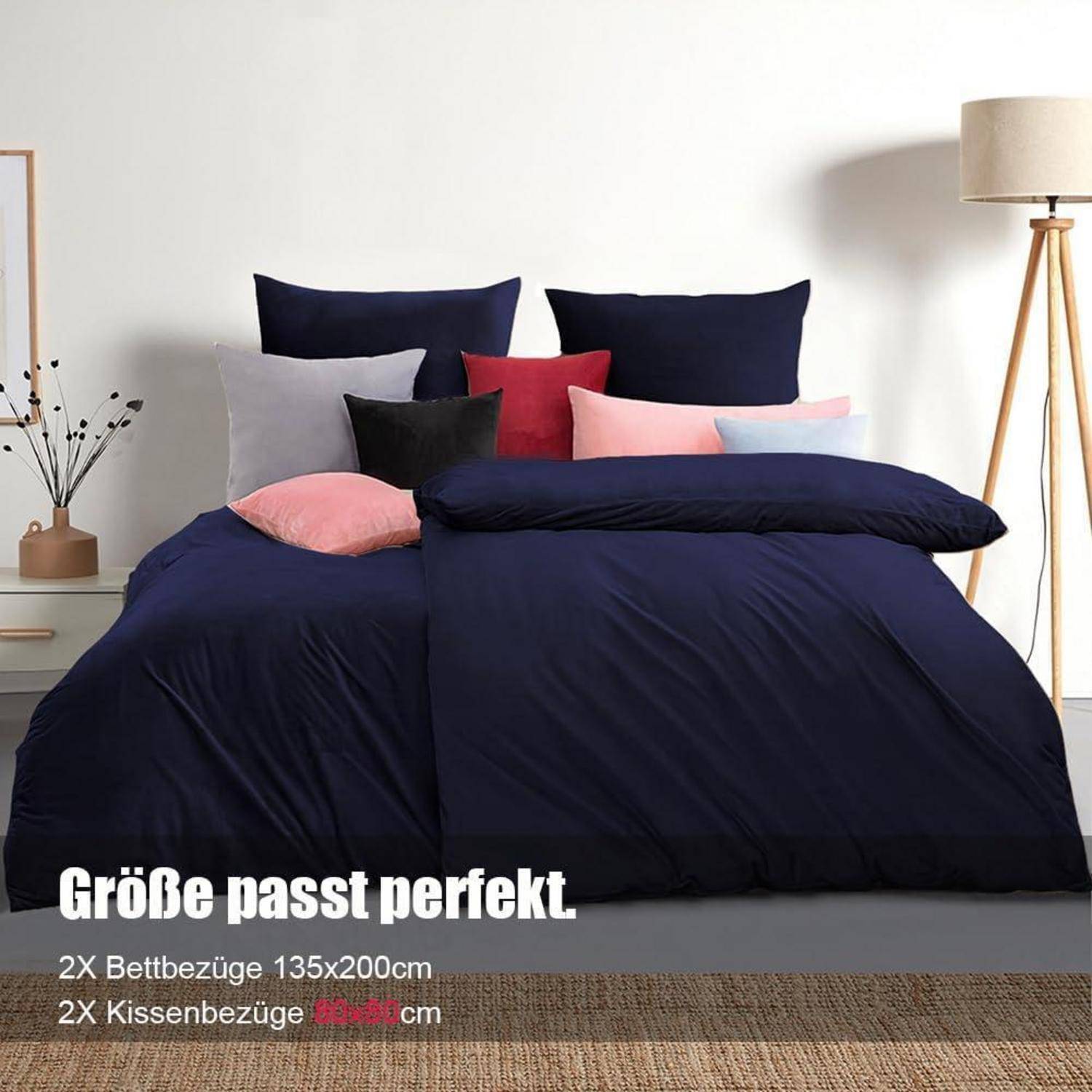 Ein sauber gemachtes Bett mit einer marineblauen Bettdecke, mehreren Kissen in Dunkelblau, Schwarz und Rosa. Text liest sich 