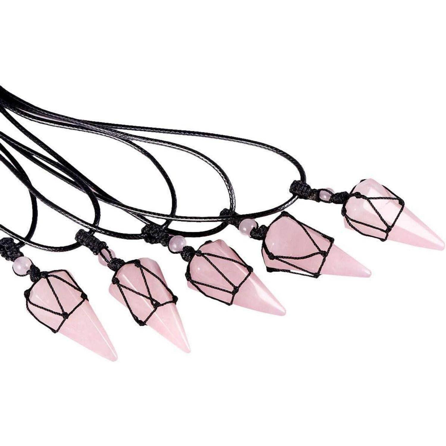 Fünf rosa Kristallanhänger, in schwarze Schnur eingewickelt, jeweils an einer schwarzen Schnur mit kleinen Perlen befestigt, in einer Reihe angeordnet.
