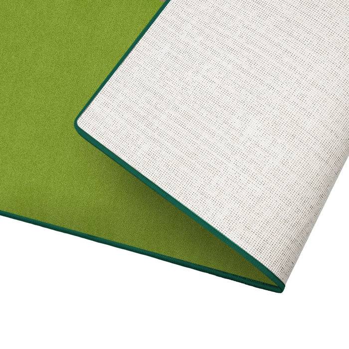 Eine zweifarbige Yogamatte wird gezeigt, mit einer grünen Oberseite und einer weißen Unterseite, die eine dezente Textur aufweist. Die Kanten sind ordentlich in Petrolblau abgenäht.