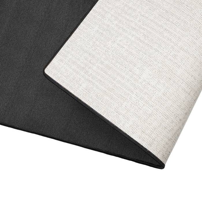 Eine Nahaufnahme eines zweifarbigen Stoffmusters, die den Kontrast zwischen einer strukturierten, hellgefärbten Oberfläche und einer glatten, dunklen Oberfläche zeigt.