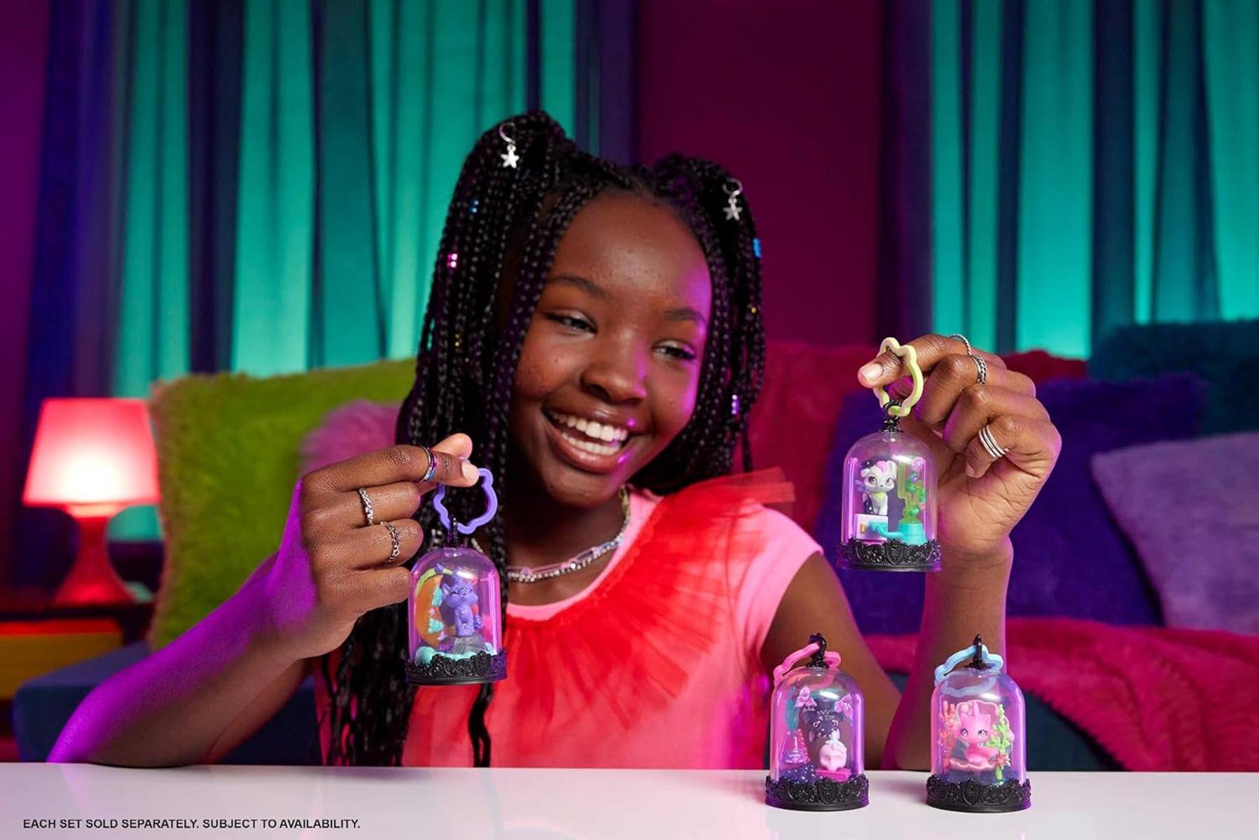 Ein lächelndes Kind hält und präsentiert Sammelfiguren, die in durchsichtigen Glaskuppeln eingeschlossen sind und verschiedene farbenfrohe und fantasievolle Designs zeigen.