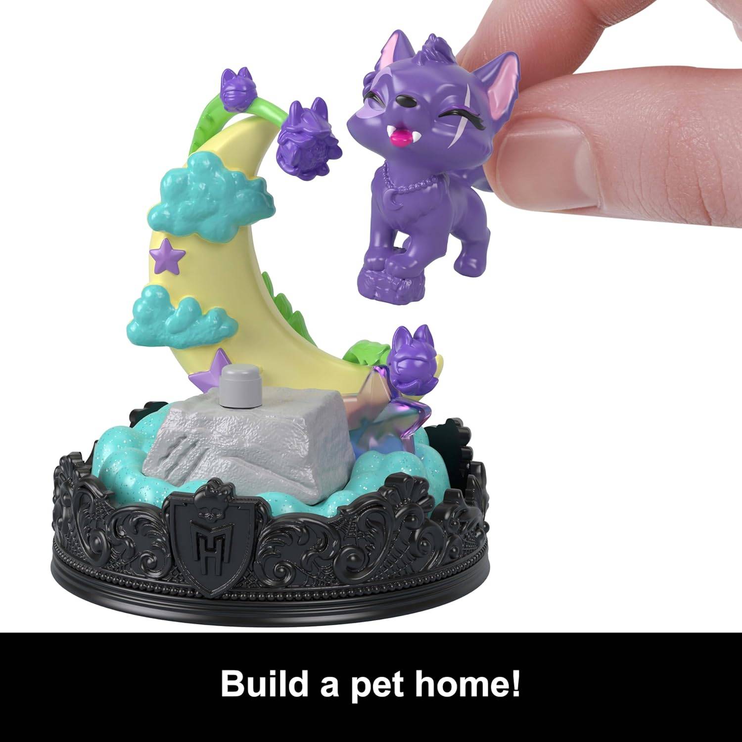 Eine Hand platziert ein kleines lila Katzenspielzeug auf einer dekorativen Plattform in Form eines Mondes. Text darunter liest sich: „Baue ein Zuhause für dein Haustier!