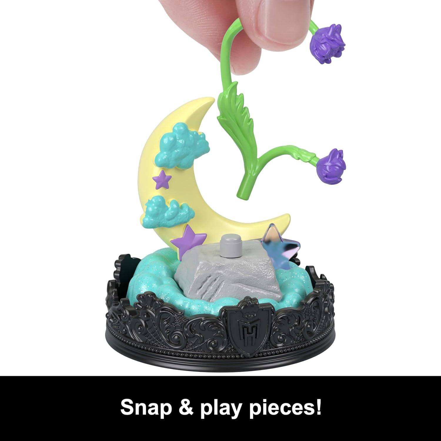 Eine Hand arrangiert ein buntes Objekt mit einer Mondsichel, Sternen und Wolken auf einer dekorativen Basis. Text darunter liest sich: Schnapp & spiel Teile!