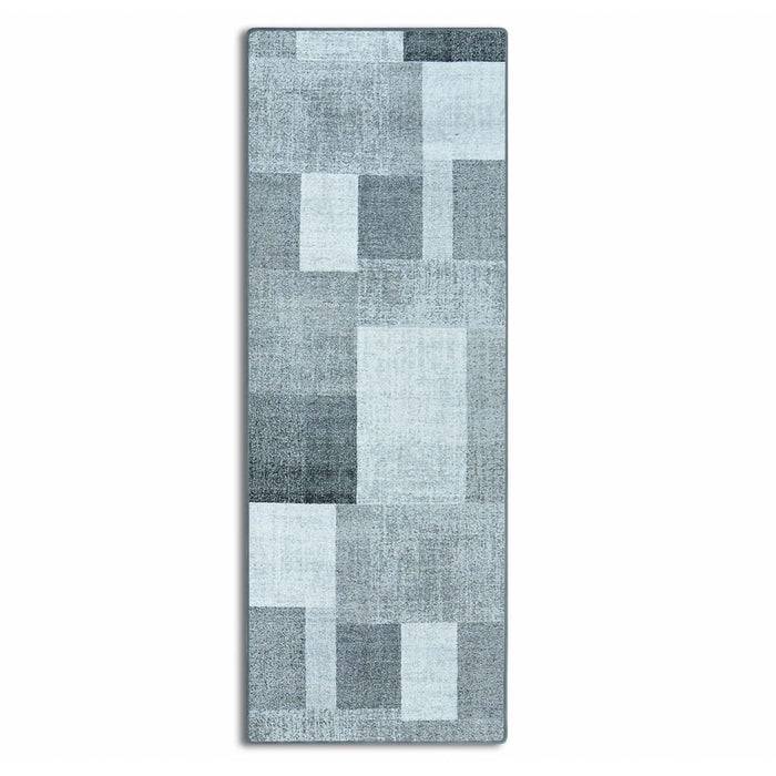 Ein rechteckiger Teppich mit einem geometrischen Muster in verschiedenen Grautönen, der sich überlappende Rechtecke zeigt und ein modernes, abstraktes Design aufweist.