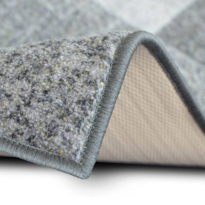 Nahaufnahme einer grauen Teppichecke, die die strukturierte Oberfläche und die rutschfeste Rückseite zeigt, wobei Materialien und Funktionalität für den Heimgebrauch hervorgehoben werden.