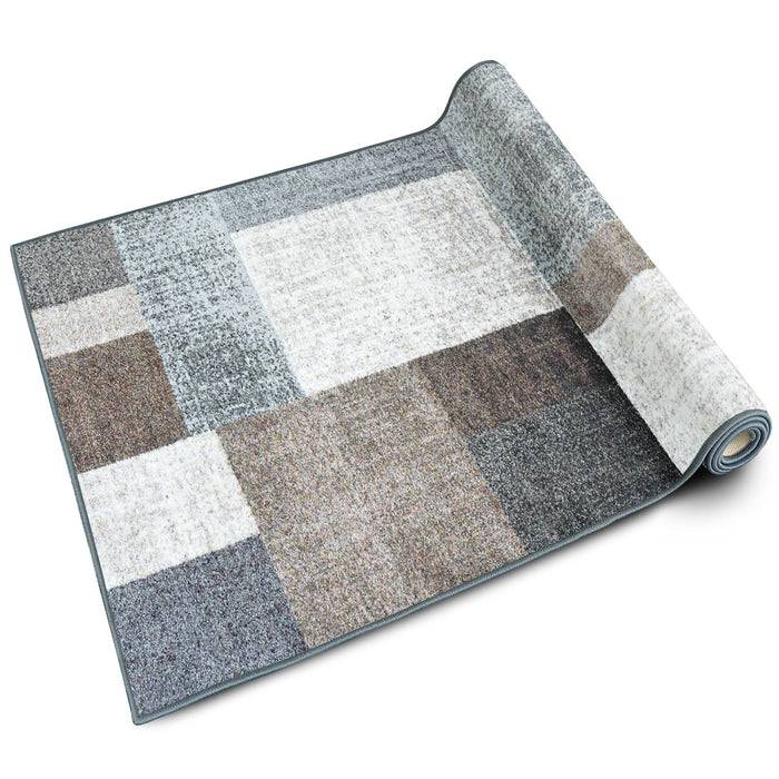 Ein gerollter rechteckiger Teppich mit einem Patchwork-Muster in Schattierungen von Grau, Creme und Braun, der ein modernes, strukturiertes Aussehen aufweist.