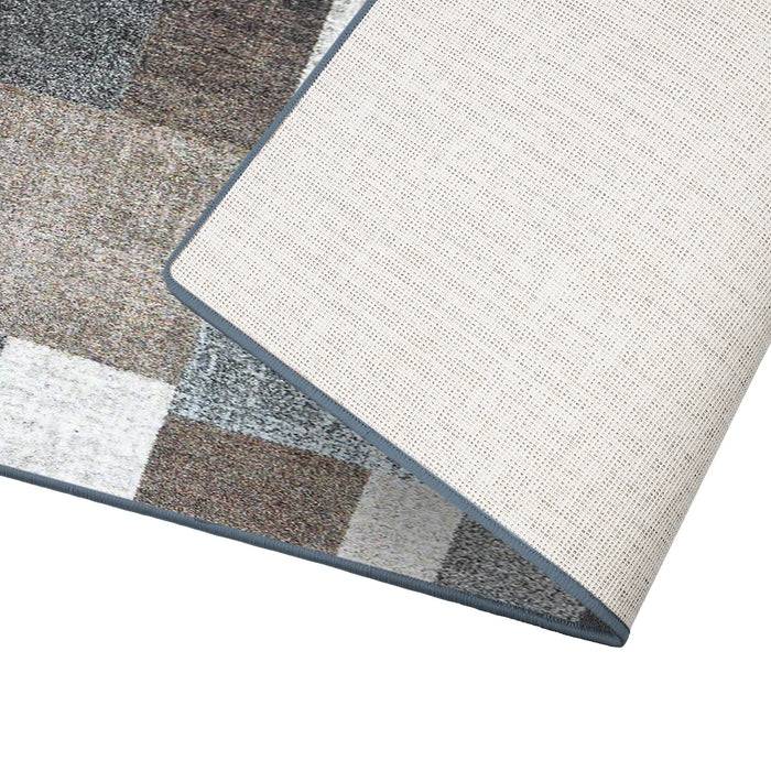 Vorder- und Rückansicht einer mehrfarbigen geometrisch gemusterten Ecke eines Teppichs, die Textur und die gewebte Unterseite in neutralen Tönen zeigend.