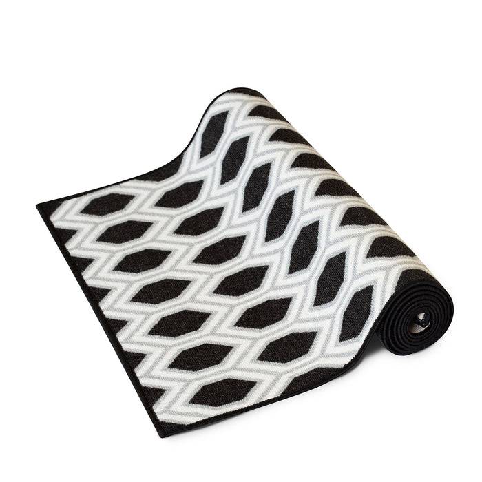 Eine schwarz-weiße geometrisch gemusterte Yogamatte ist teilweise aufgerollt und zeigt ihr Rautenmuster.