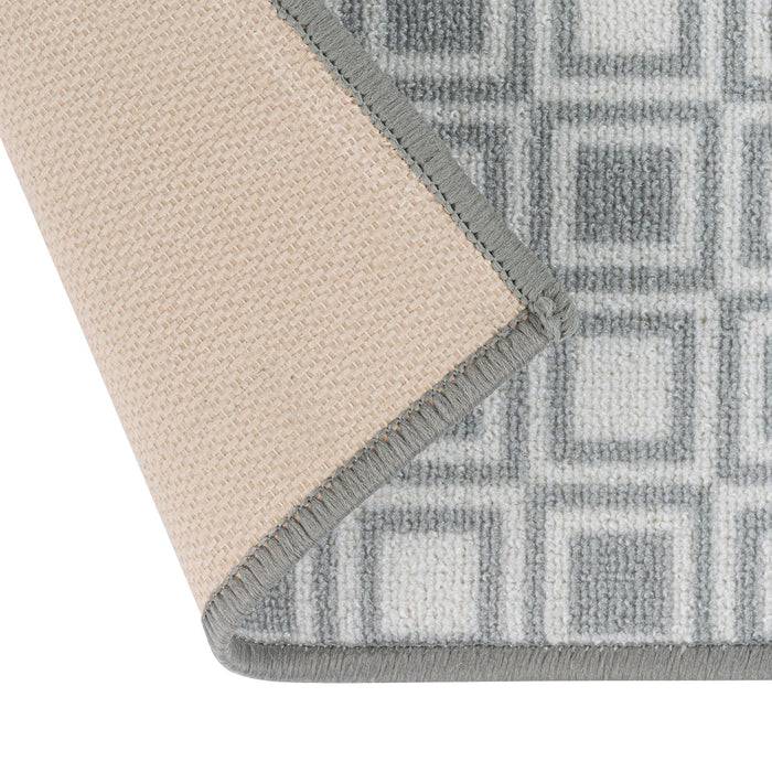 Ein grau und beige karierter Teppich ist teilweise übergefaltet und zeigt die Rückseite. Der Rand hat eine graue Einfassung.