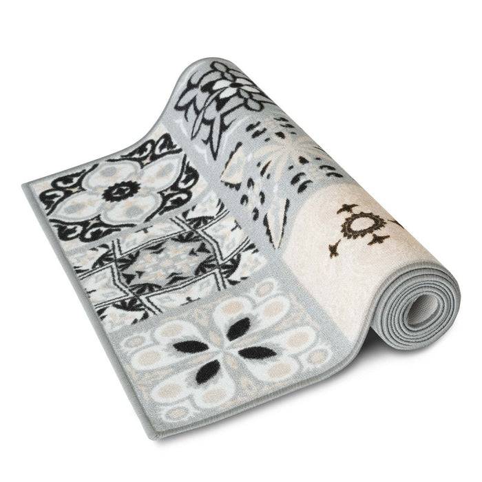 Ein aufgerollter, gemusterter Teppich mit geometrischen und floralen Designs in Schwarz und Weiß, der auf einem einfarbigen weißen Hintergrund liegt.