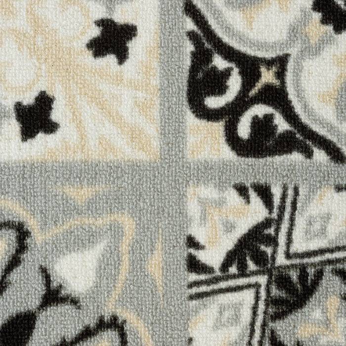 Eine Nahaufnahme eines strukturierten Stoffes mit einem geometrischen und floralen Muster in schwarzen, grauen und beigen Tönen, in vier Quadrate unterteilt.