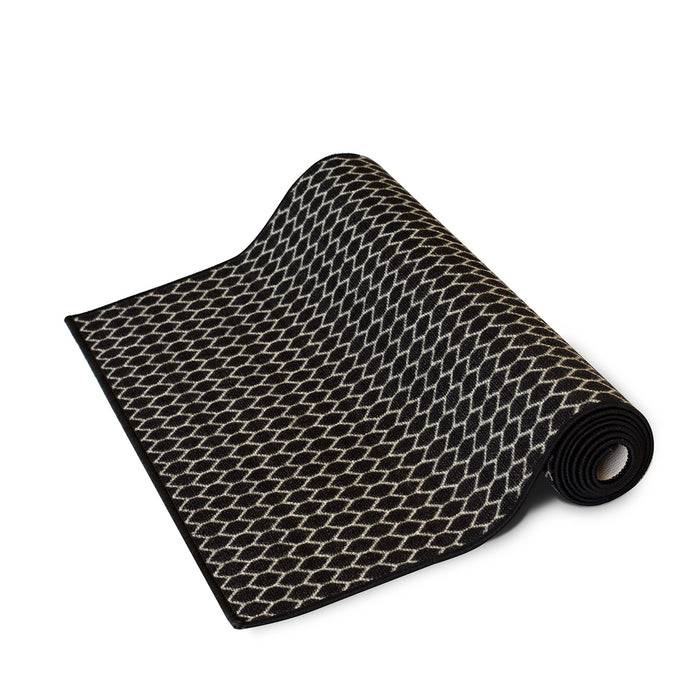 Ein aufgerollter schwarzer Teppich mit einem weißen geometrischen Muster, das eine Reihe von ineinandergreifenden Rauten zeigt.