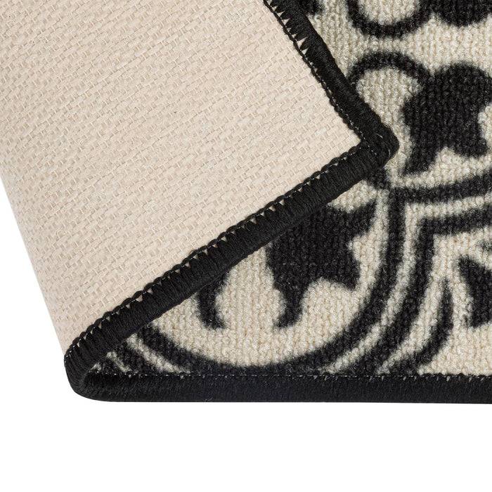 Eine Nahaufnahme eines schwarz-weiß gemusterten Teppichs, bei der eine Ecke angehoben ist und die strukturierte Unterseite sichtbar wird.