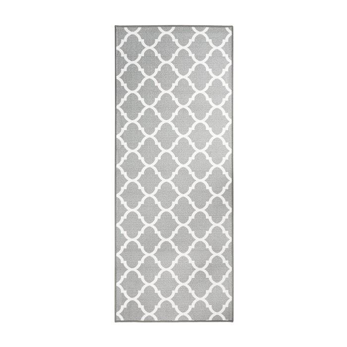 Ein rechteckiger grauer Teppich mit einem weißen Gittermuster, der ineinandergreifende geometrische Formen in einem symmetrischen Design aufweist.