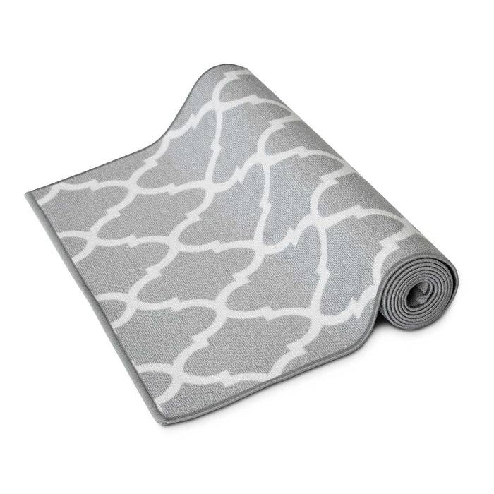 Eine aufgerollte graue Yogamatte mit einem weißen geometrischen Muster, teilweise ausgerollt, die ihre Textur und ihr Design zeigt.