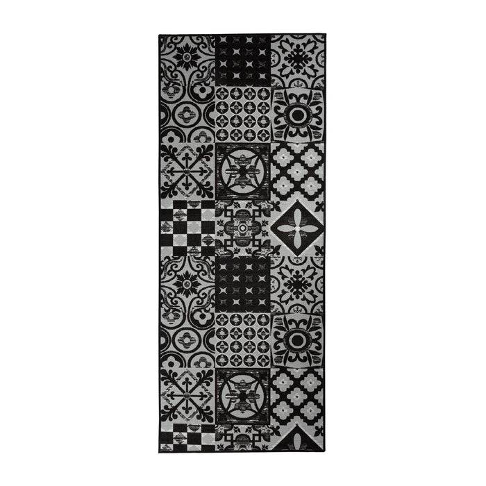 Ein rechteckiger Teppich mit einer Mischung aus schwarzen und weißen geometrischen und floralen Mustern, die in einem Patchwork-Stil angeordnet sind.