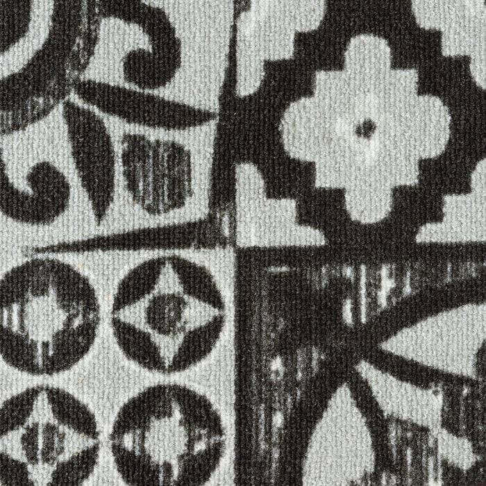 Eine Nahaufnahme eines gemusterten Stoffes mit geometrischen Formen und Blumenmotiven in Schwarz-, Grau- und Weißtönen.