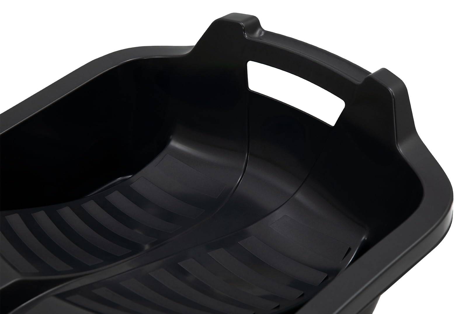 Eine Nahaufnahme eines schwarzen Kunststoff-Schlittens mit Griff und gerillter Innenfläche, der zum Rutschen auf Schnee konzipiert ist.