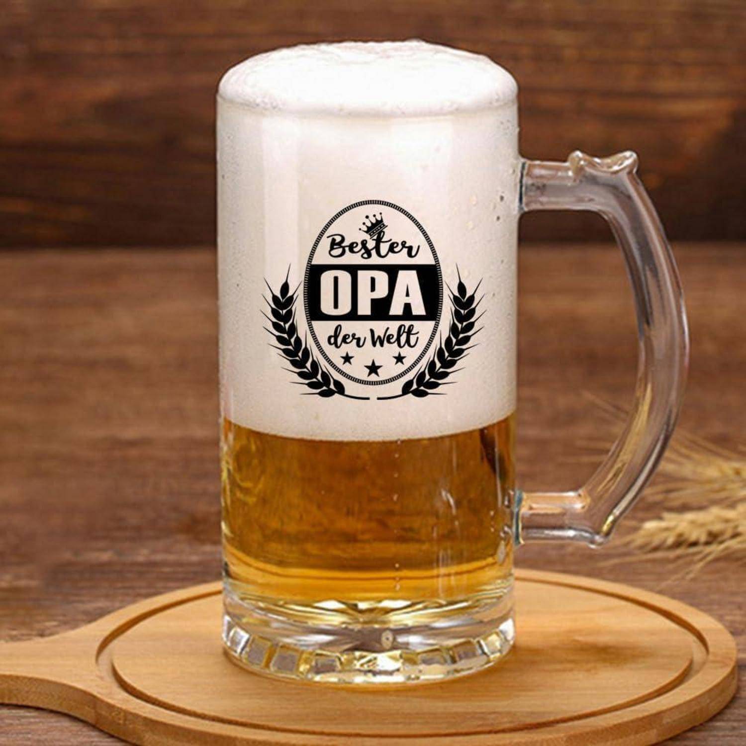 Ein Bierglas, gefüllt mit schaumigem Bier, steht auf einem Holzuntersetzer. Der Krug trägt die Aufschrift 'Bester Opa der Welt' mit einem dekorativen Emblem.