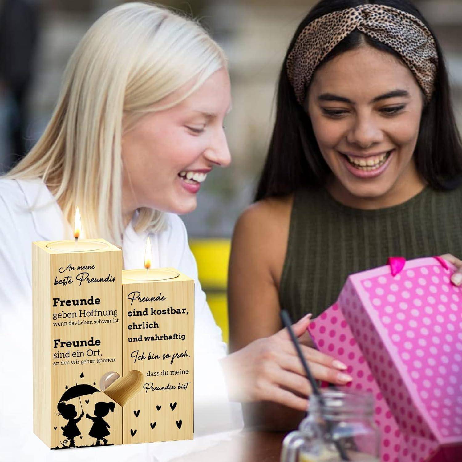 Zwei Frauen lächeln und betrachten eine Grußkarte mit einem Zitat über Freunde, die wertvoll und vertrauenswürdig sind, mit Kerzenmotiven.