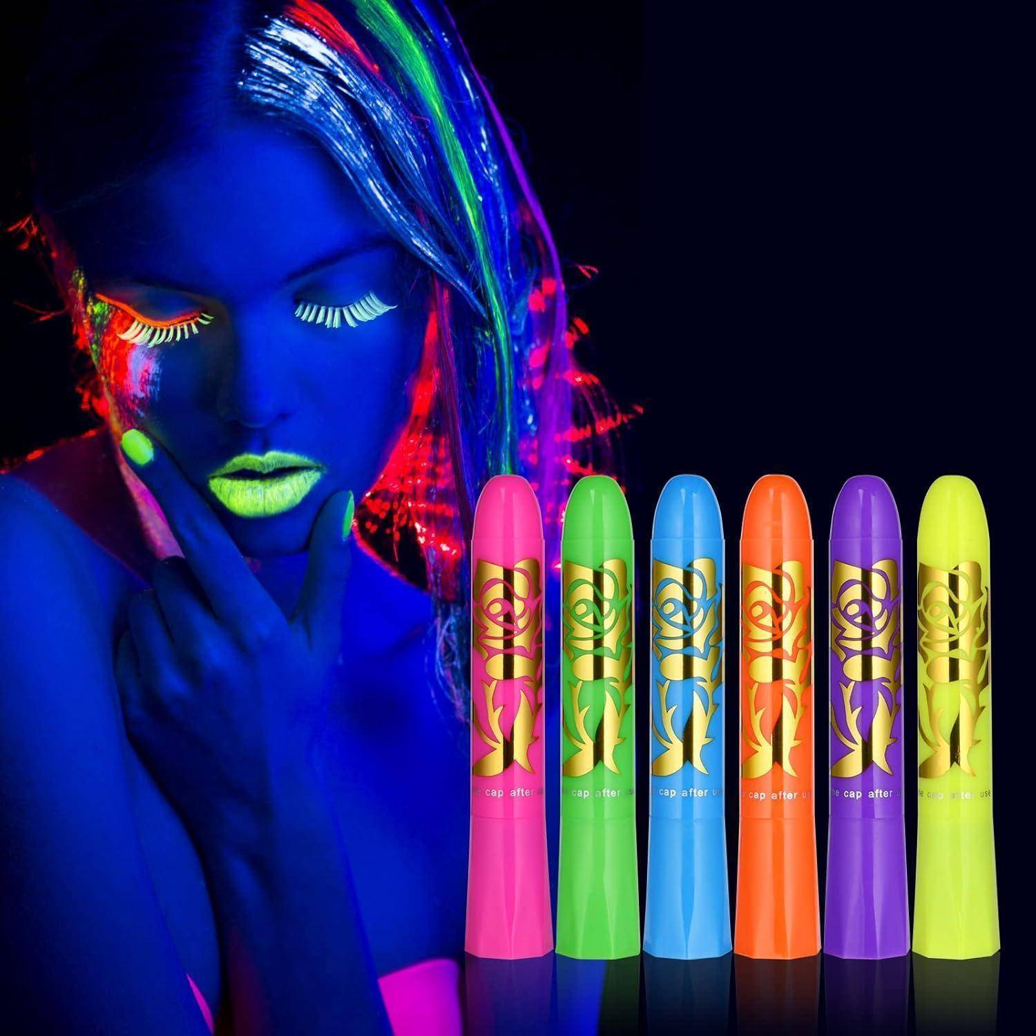 Eine Person mit Neon-Make-up und im Dunkeln leuchtender Gesichtsfarbe steht neben sechs bunten Neon-Leuchtstäben vor einem dunklen Hintergrund.