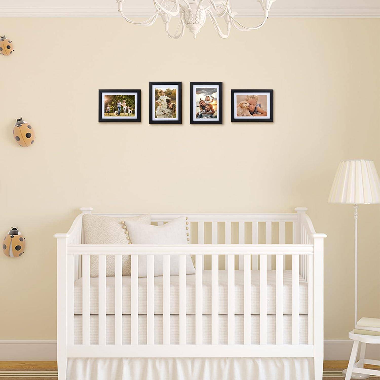 Ein weißes Babybett in einem Kinderzimmer mit einer weißen Lampe rechts davon. Familienfotos in schwarzen Rahmen sind an der Wand über dem Kinderbett aufgehängt.