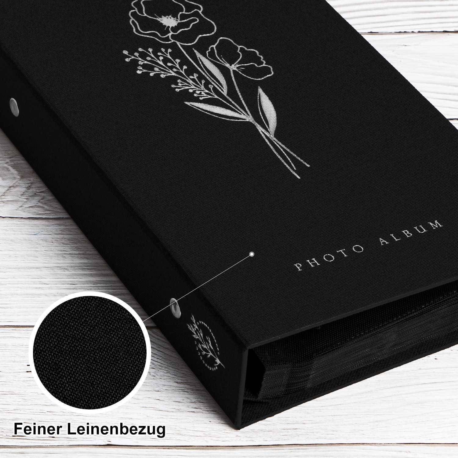 Ein schwarzes Fotoalbum mit einem Blumenmuster auf dem Einband, beschriftet mit 'FOTOALBUM'. Einsetzbild zeigt eine Nahaufnahme des strukturierten Gewebes.