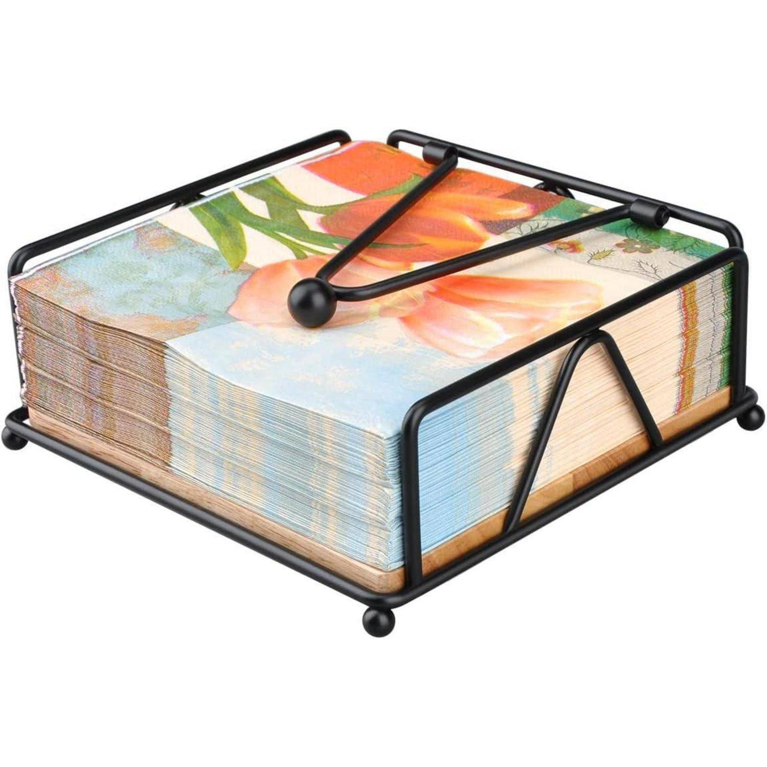 Ein Stapel bunter, mit Blumenmuster bedruckter Servietten in einem schwarzen Metallservettenhalter, der auf einer flachen Oberfläche ruht.