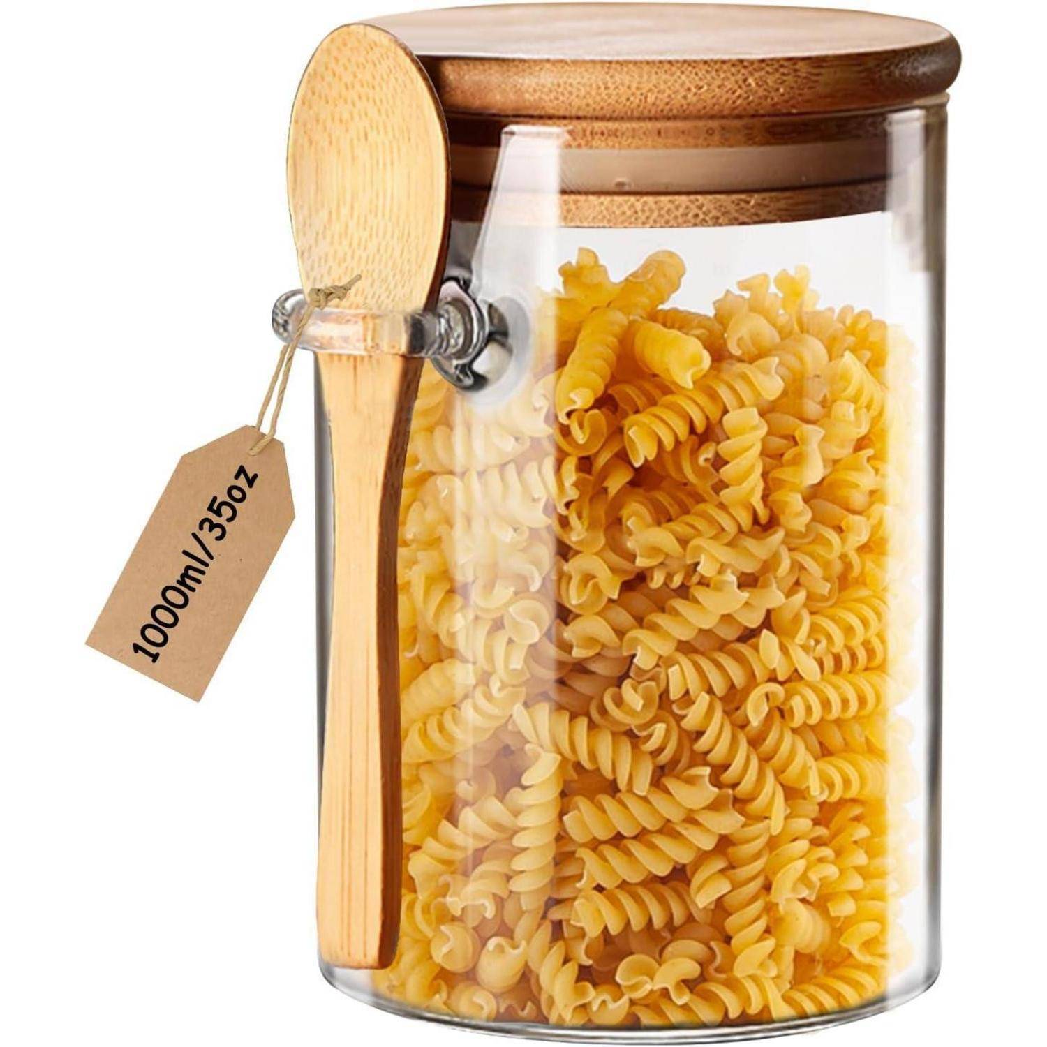 Ein Glasgefäß gefüllt mit Spiralnudeln, verschlossen mit einem Holzdeckel, hat einen Holzlöffel daran befestigt. Ein Anhänger zeigt '1000ml/35oz'.