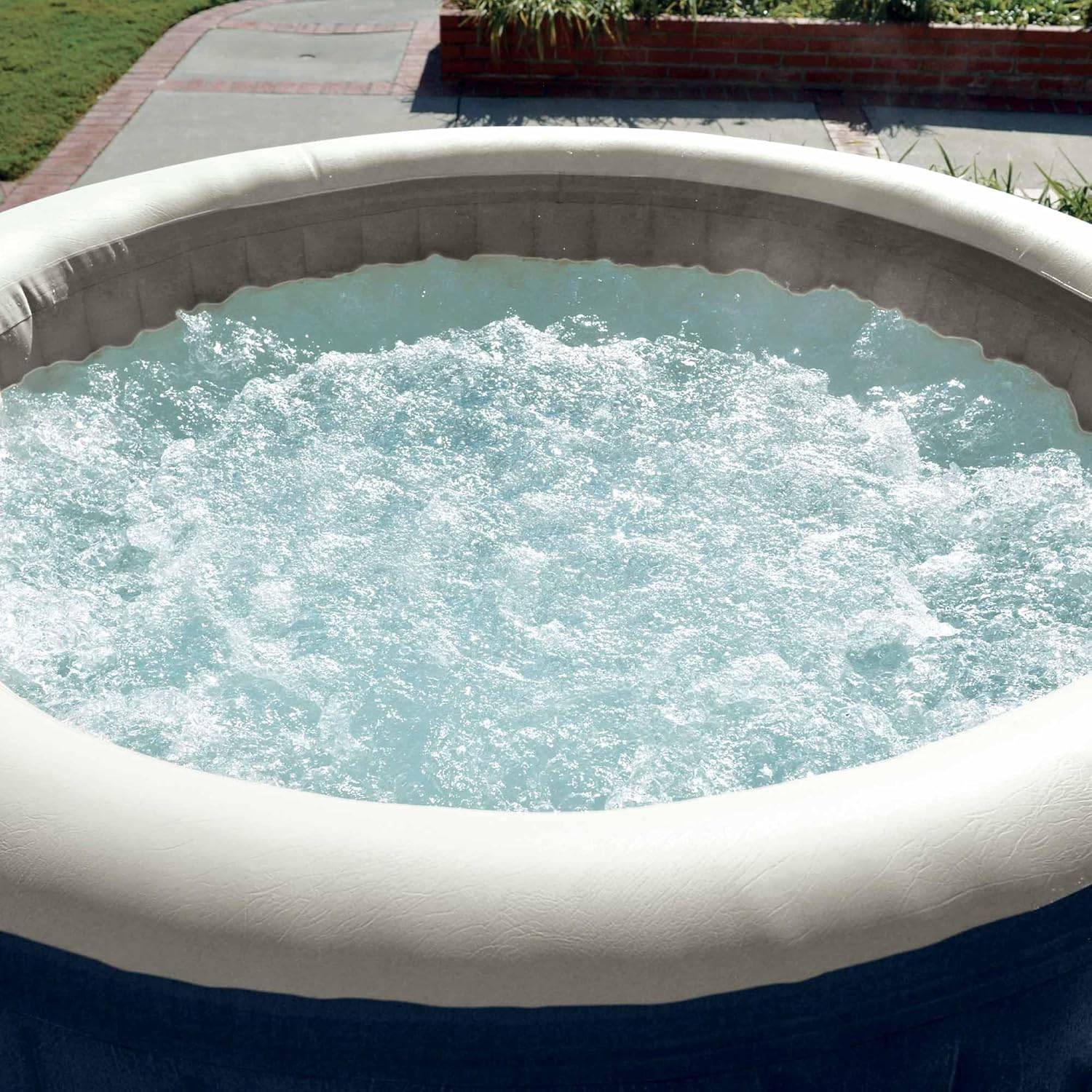 Eine sprudelnde, kreisförmige Außen-Whirlpool, gefüllt mit Wasser, auf einer Terrasse mit einem Garten im Hintergrund.