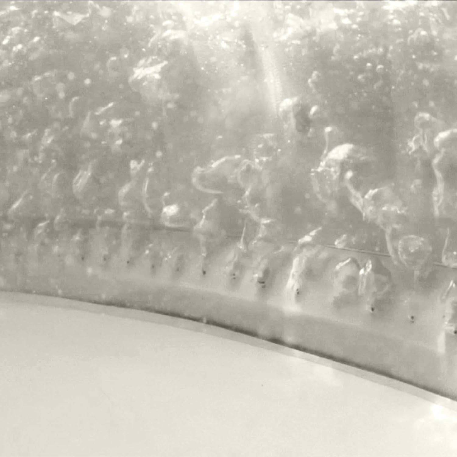 Nahaufnahme einer strukturierten, glänzenden Oberfläche eines metallischen Zylinders mit Wassertropfen, was auf Kondensation oder eine feuchte Umgebung hindeutet.