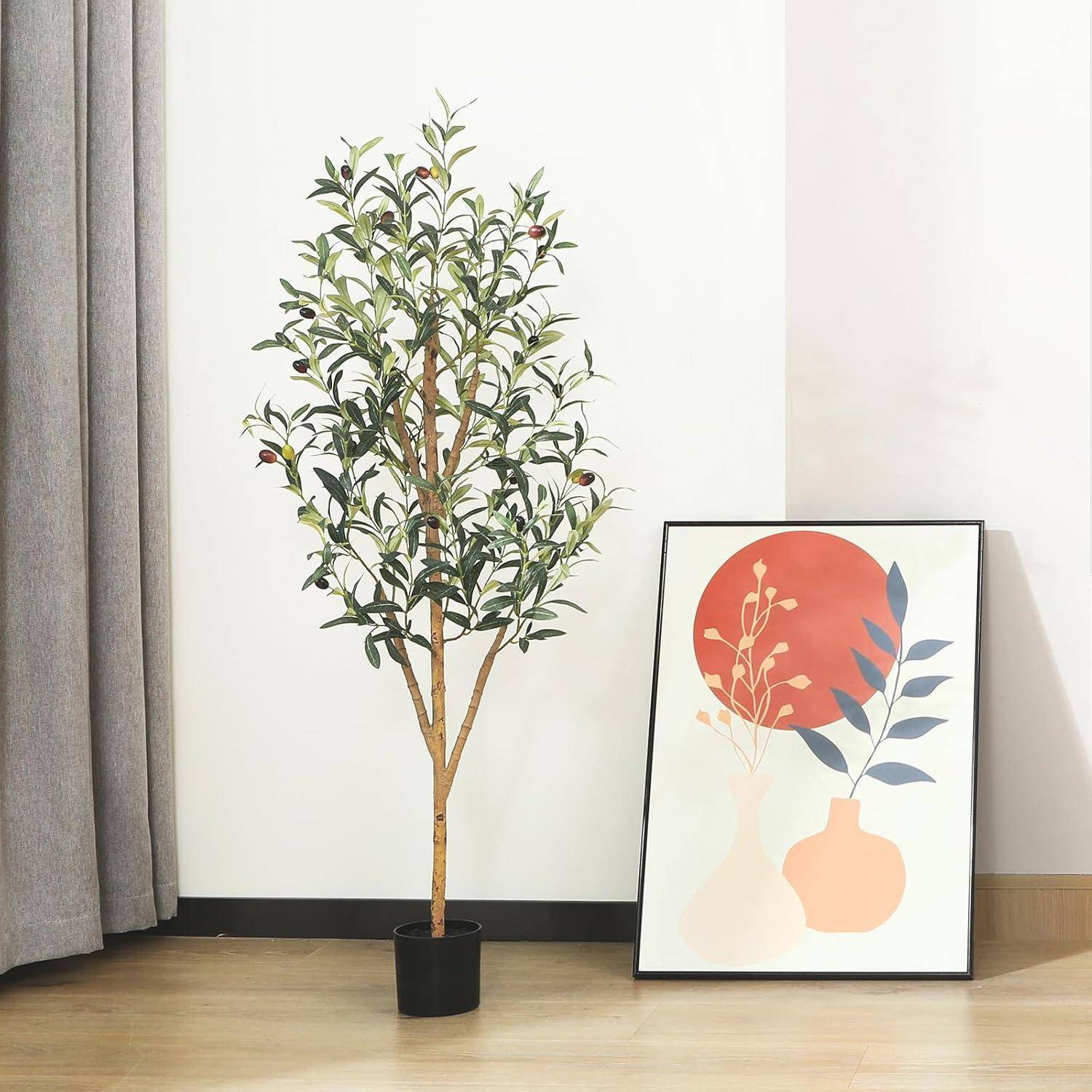 Eine Zimmerpflanze steht neben einem gerahmten abstrakten Kunstwerk mit orange und grauen Formen, vor einer hellen Wand mit einem Vorhang.