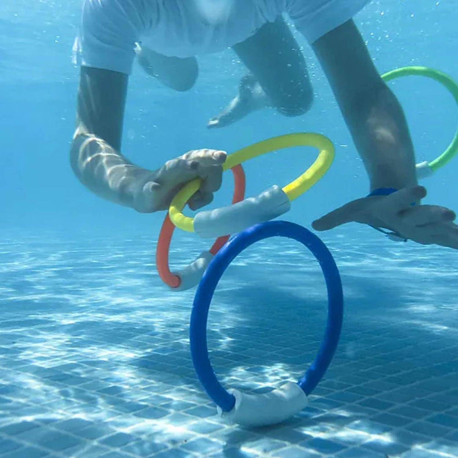 Eine Person unter Wasser greift nach bunten Ringen, die knapp über dem Poolboden schweben und damit eine Wasseraktivität veranschaulicht.