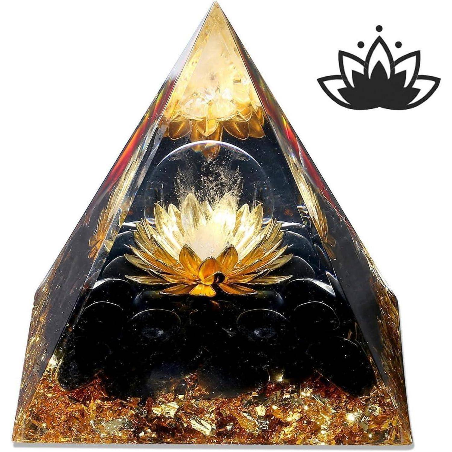 Eine pyramidenförmige Orgonit mit goldenem Blumendesign im Inneren. Schwarze Steine sind an der Basis eingebettet. Ein Lotussymbol befindet sich in der oberen rechten Ecke.