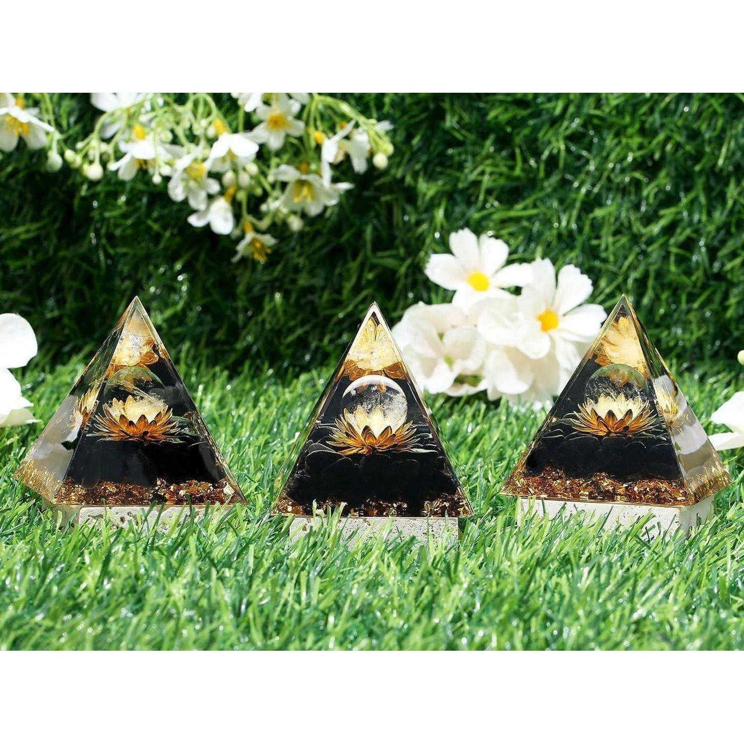 Drei dekorative, pyramidenförmige Objekte mit Blumenmustern werden auf Gras ausgestellt, umgeben von weißen Blumen im Hintergrund.