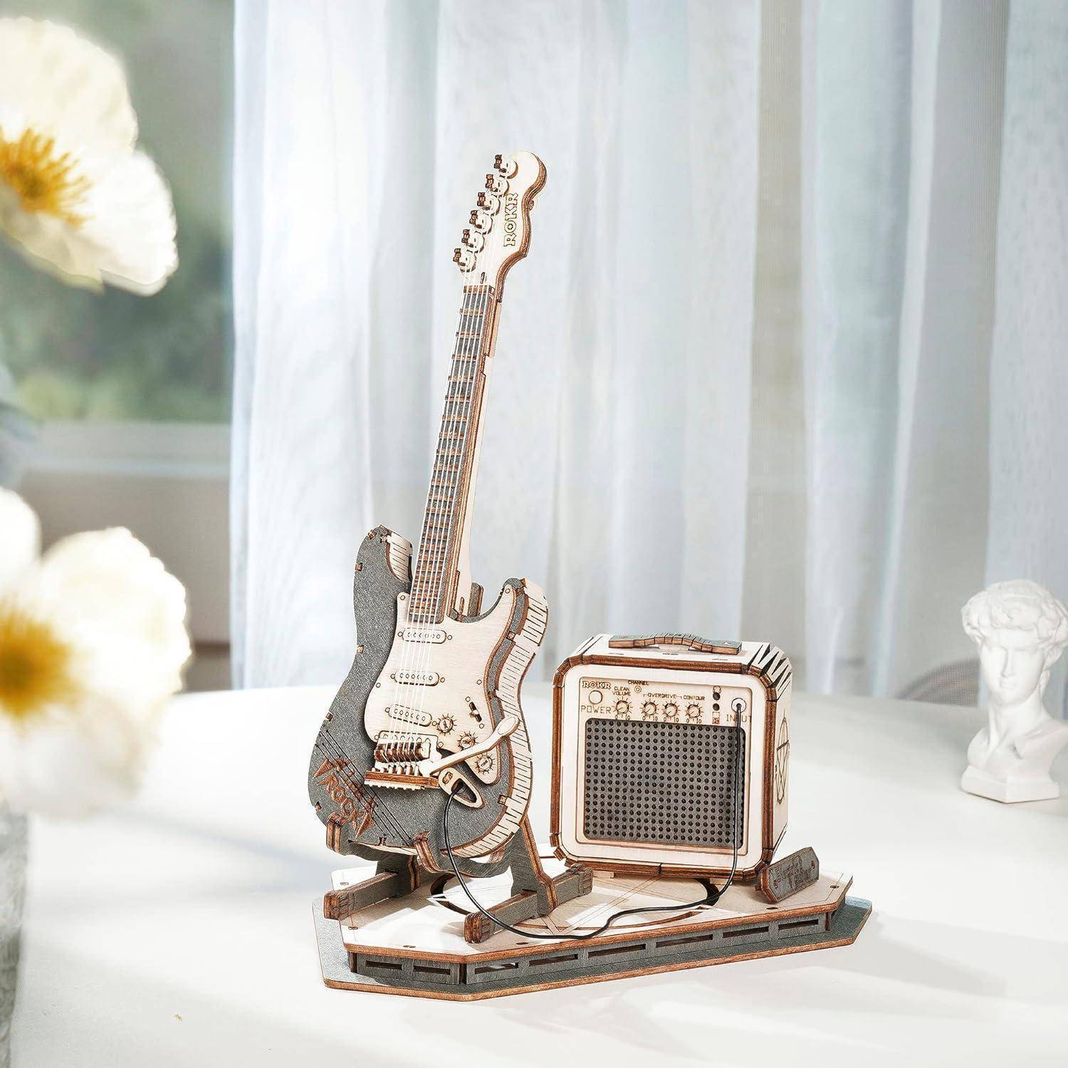 Ein detailliertes Modell einer E-Gitarre und eines Verstärkers, die auf einem Tisch platziert sind, wobei weiches Licht eine ruhige Atmosphäre im Raum erzeugt.
