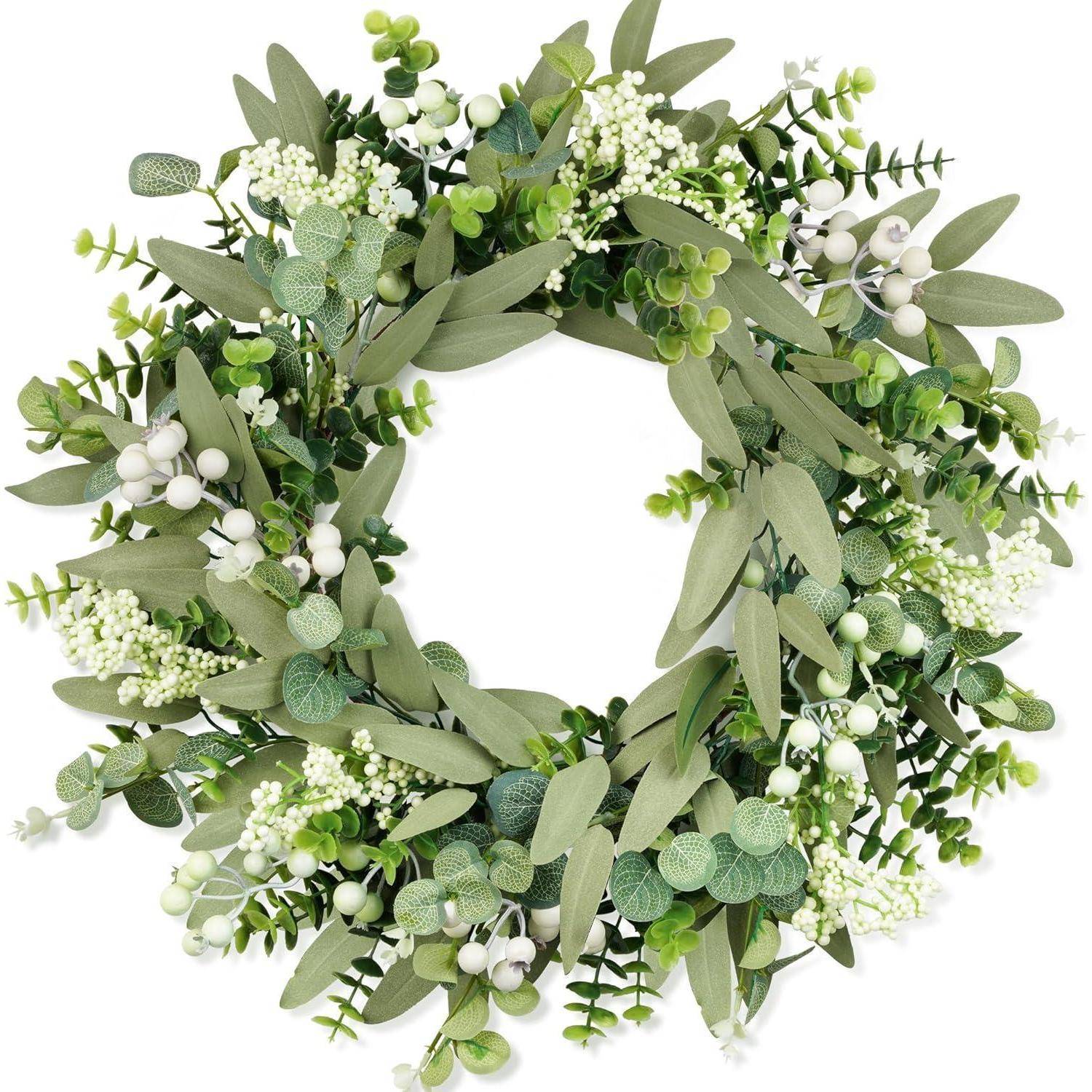 Ein Kranz in Kreisform mit verschiedenen grünen Blättern und kleinen weißen Blüten, der eine festliche und natürliche Dekoration schafft.