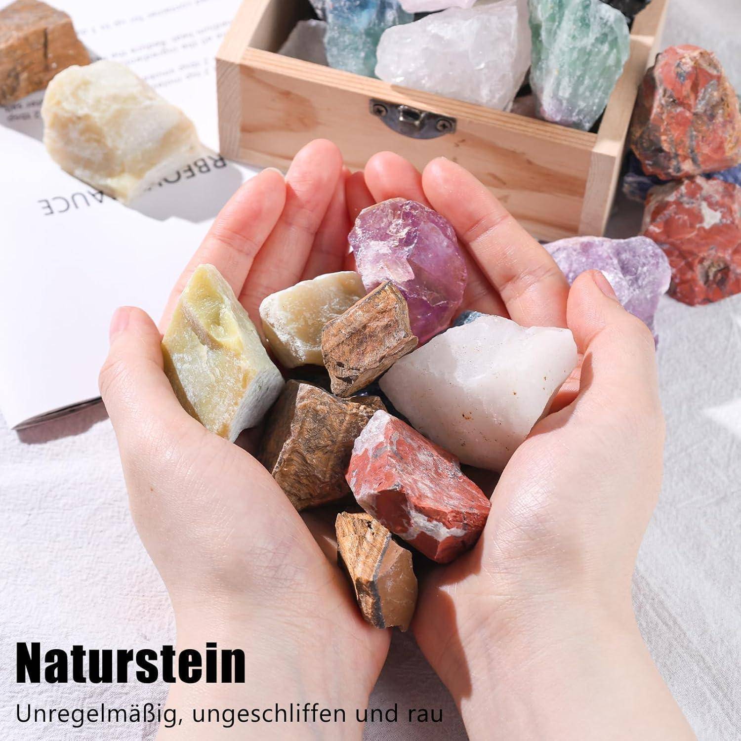 Hände halten verschiedene raue, ungeschliffene Steine. Eine Holzkiste mit ähnlichen Steinen befindet sich im Hintergrund. Text: 'Naturstein'.
