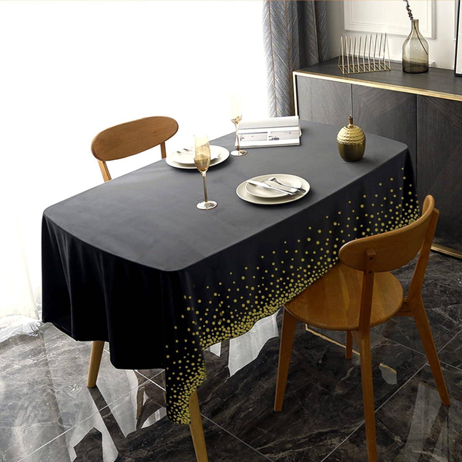 Ein Esstisch mit einer schwarzen Tischdecke, die mit goldenen Punkten verziert ist, gedeckt mit Gläsern und einem Teller, umgeben von Holzstühlen in einem modernen Ambiente.