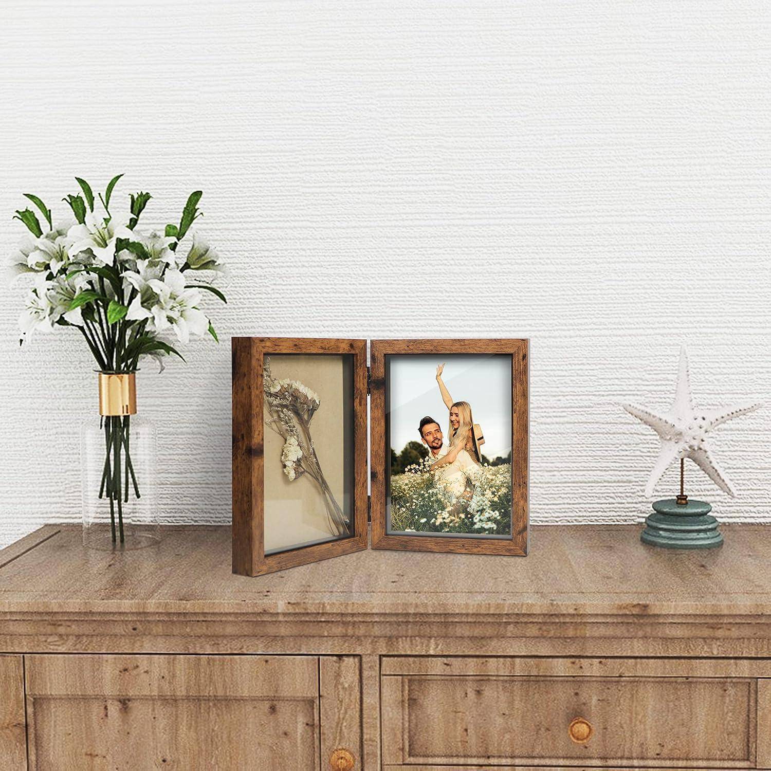 Ein Holztisch mit einer Vase voller weißer Blumen, einem gerahmten Federkunstwerk, einem Foto eines lächelnden Paares auf einer Wiese und einer Seestern-Dekoration.