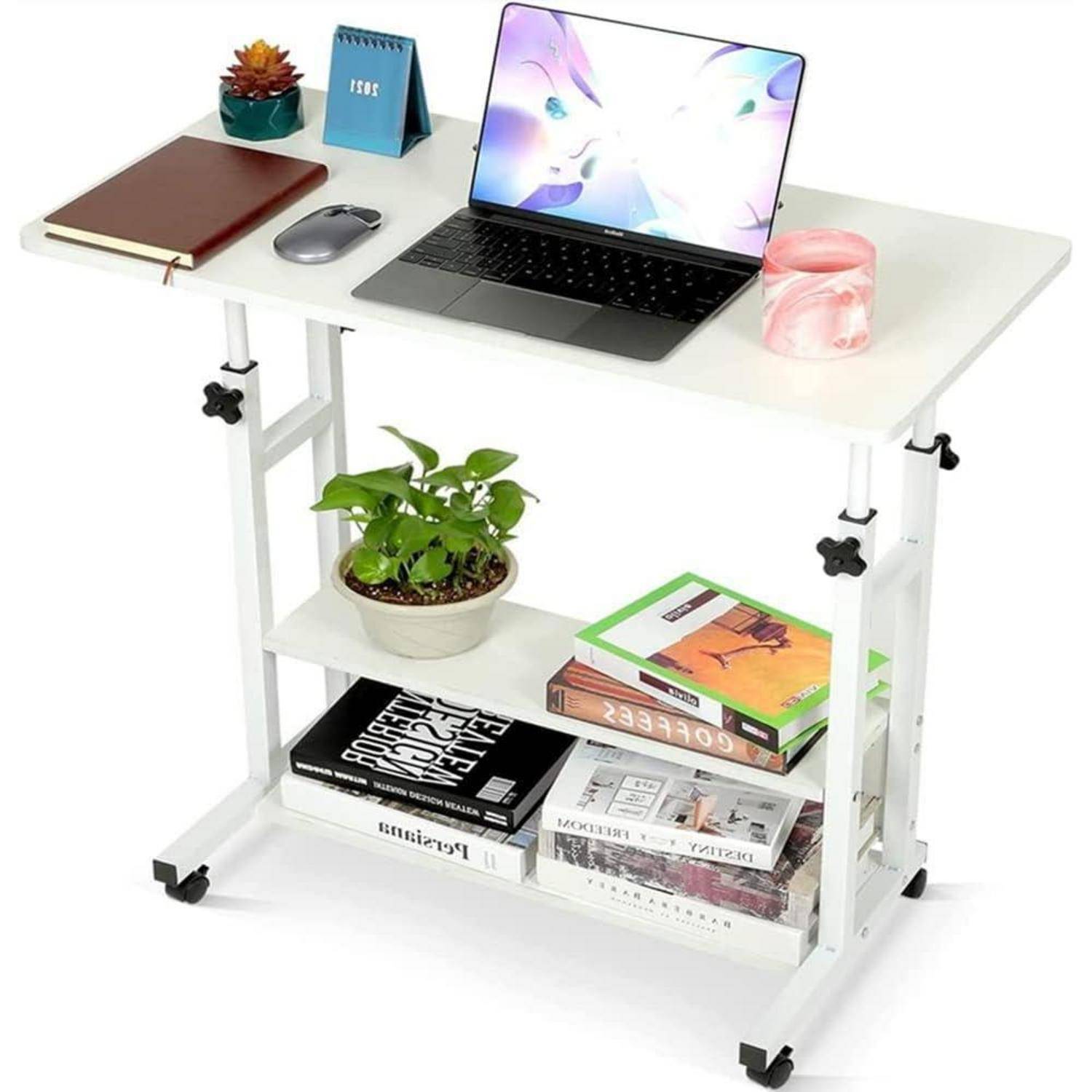 Ein weißer Schreibtisch mit einem Laptop, Notizbuch, Maus und einer Tasse oben drauf. Regale darunter beherbergen eine kleine Pflanze und Bücher. Der Schreibtisch steht auf Rollen.