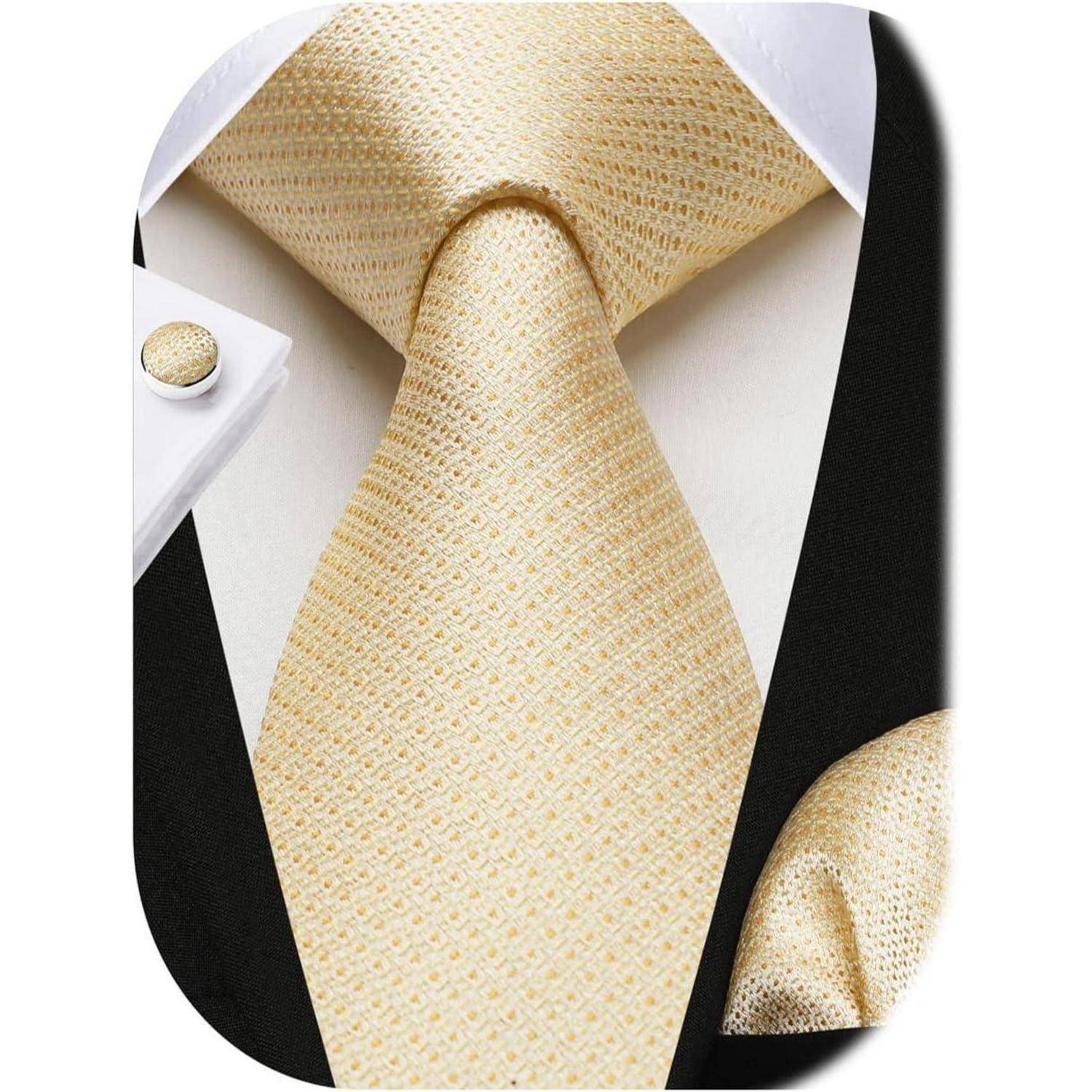 Eine Nahaufnahme einer beigen Krawatte mit Textur, kombiniert mit passendem Einstecktuch und Manschettenknöpfen auf einem weißen Hemd und schwarzen Jackett, die eine formelle Garderobe präsentiert.