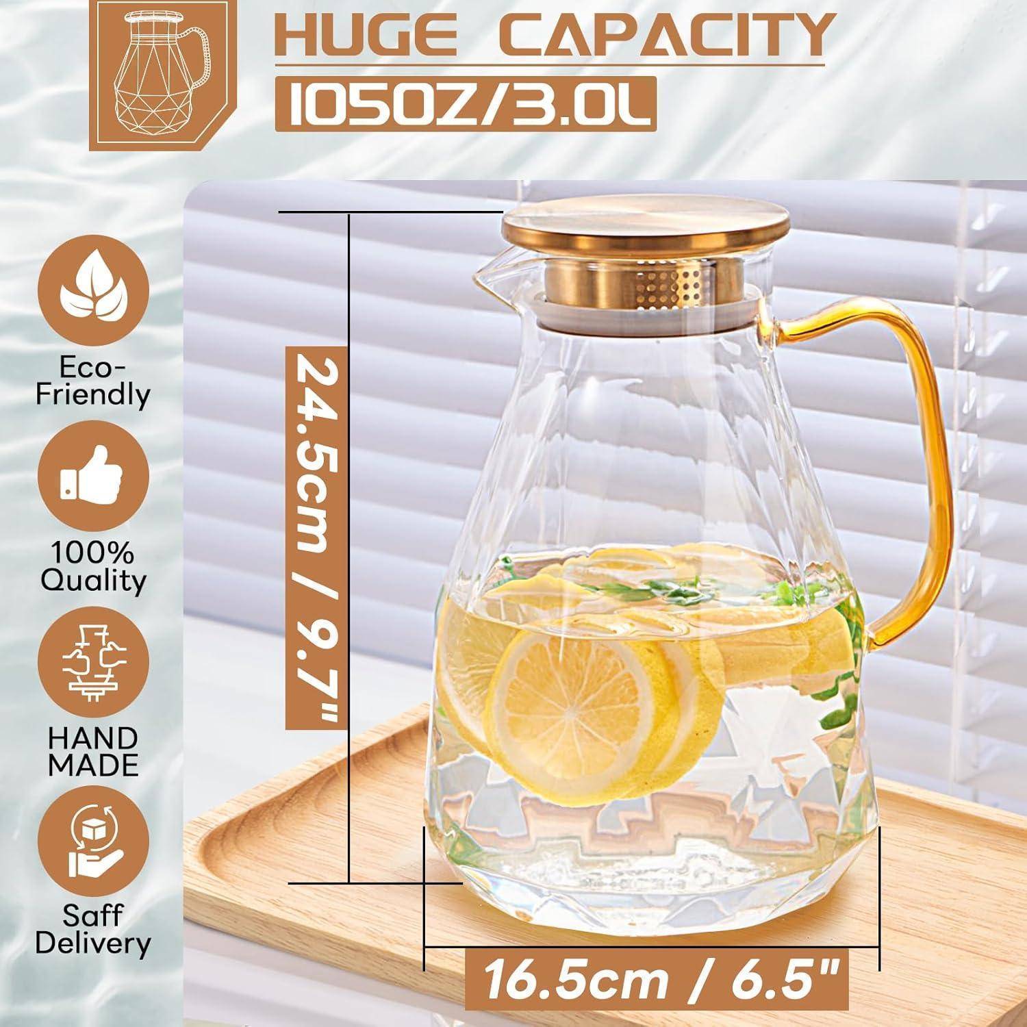 Glaskrug mit goldenem Griff und Deckel, gefüllt mit Zitronenscheiben und Kräutern in Wasser. Merkmale umfassen 'Umweltfreundlich', '100% Qualität', 'Handgefertigt' und 'Sichere Lieferung'. Fassungsvermögen: 105oz/3,0L.