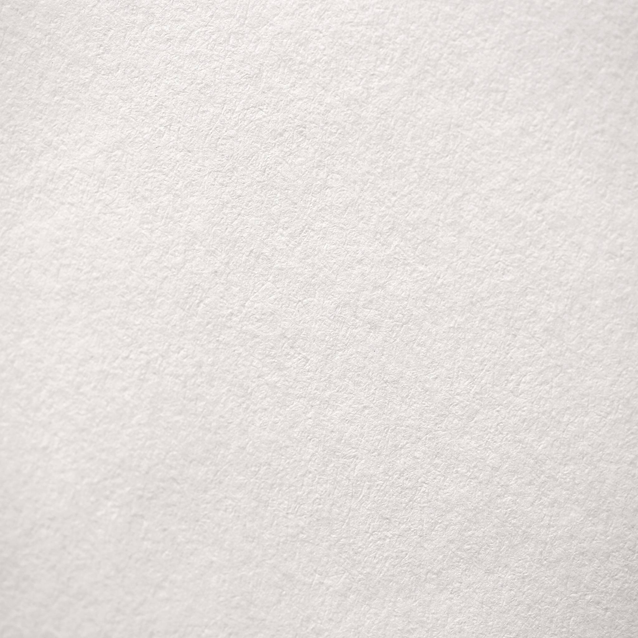 Eine Nahaufnahme eines strukturierten, leeren weißen Blattes Papier, das seine faserige Oberfläche zeigt.