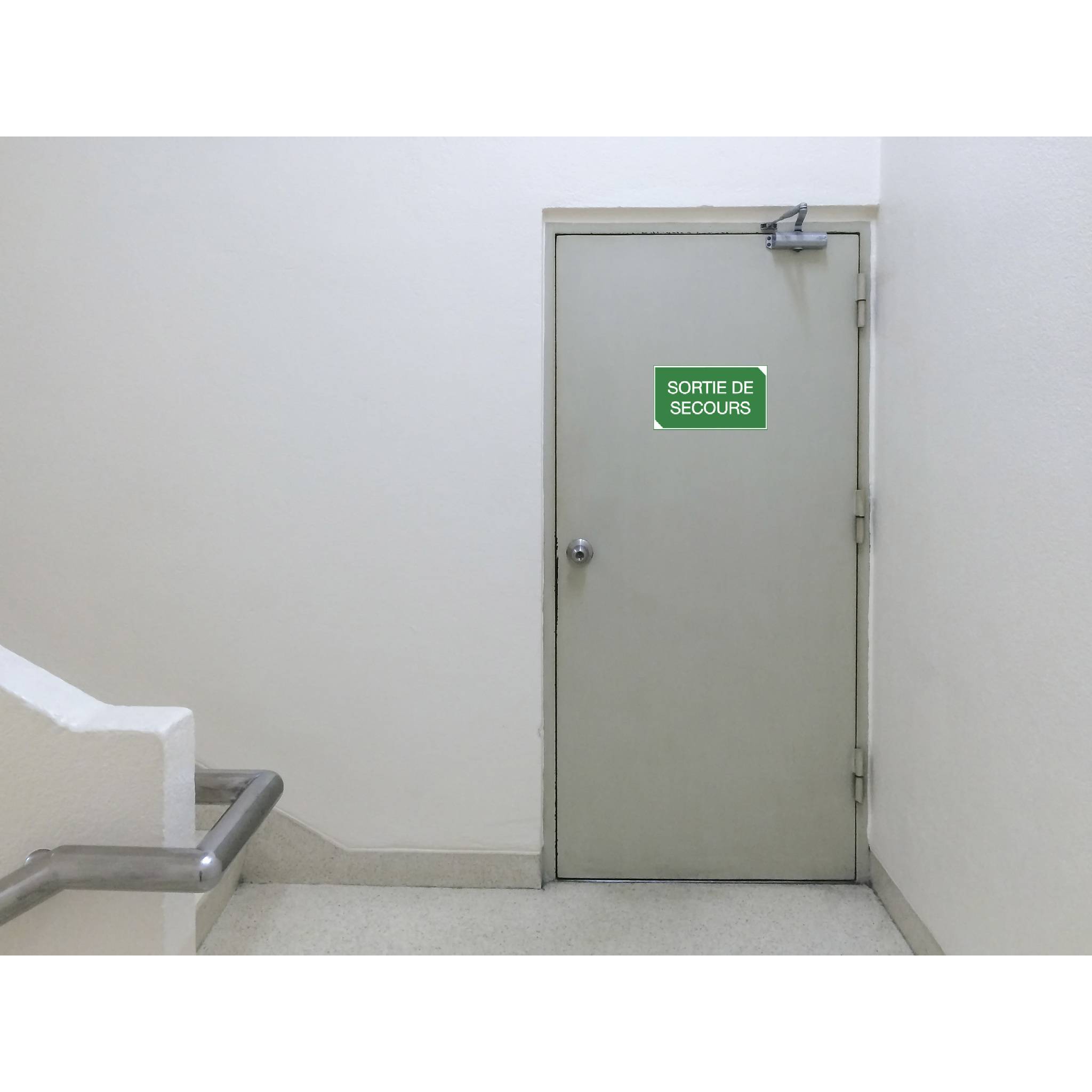 Notausgang in einem weißen Flur mit einem grünen Schild, auf dem 