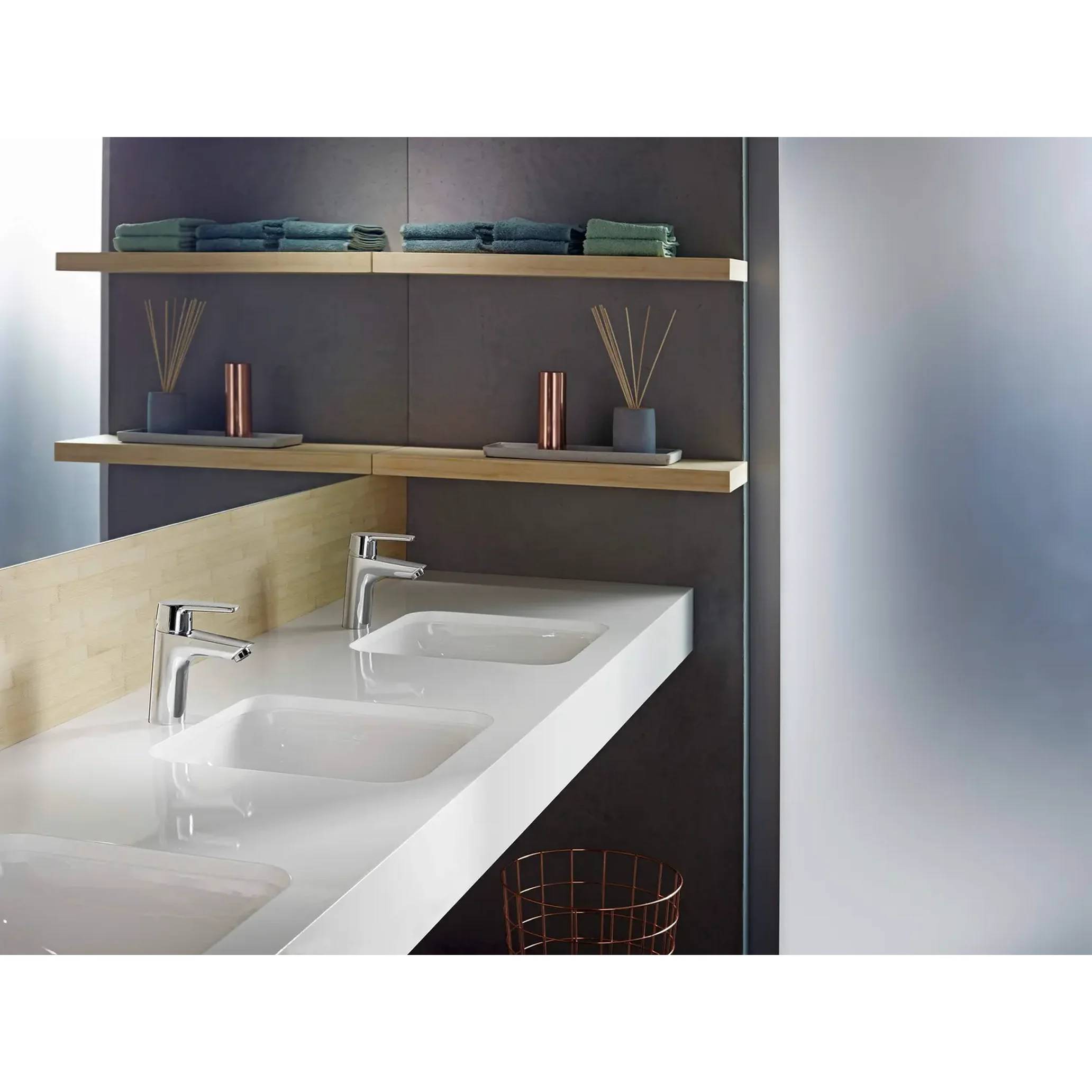 Modernes Badezimmersideboard mit zwei weißen Waschbecken, Chromarmaturen, Wandregalen und ordentlich gefalteten Handtüchern und Dekoration.