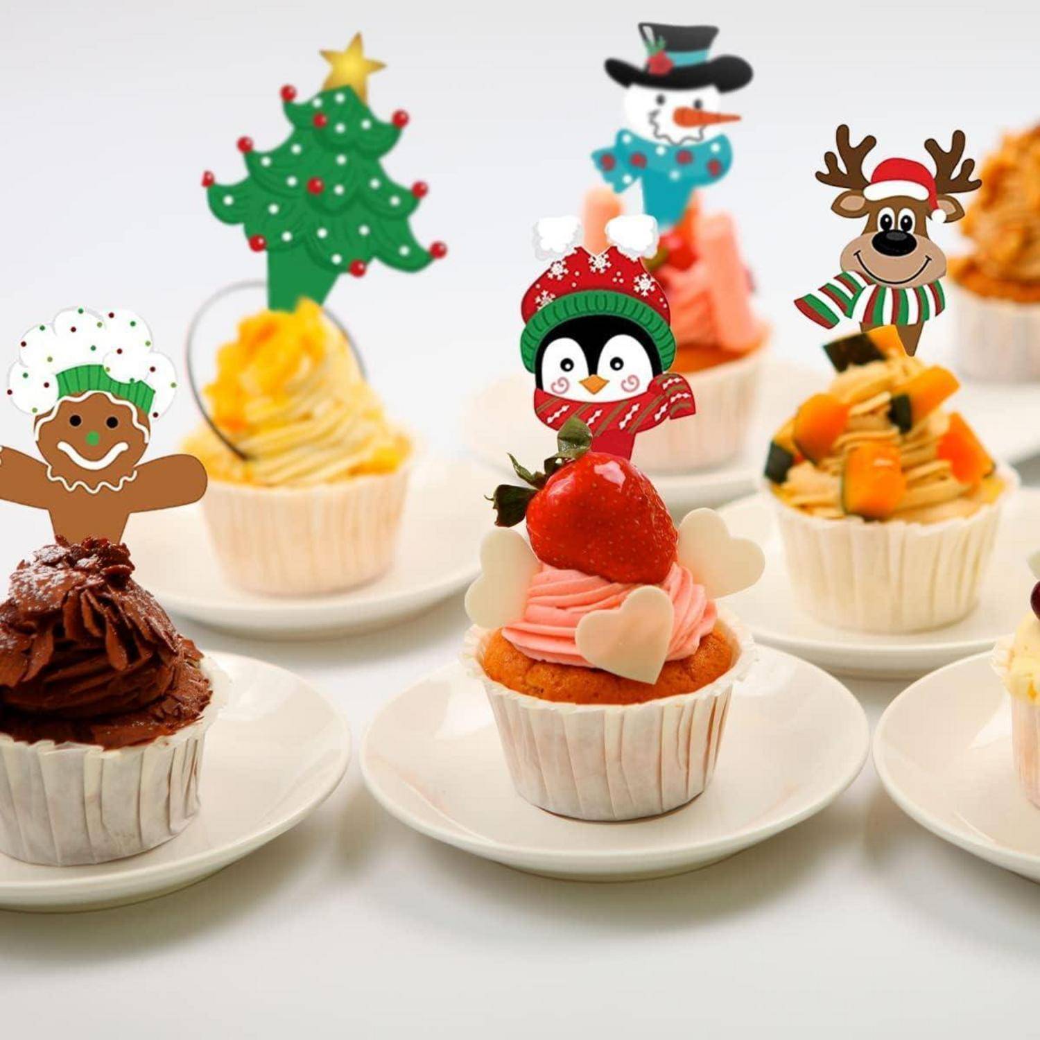 Cupcakes, die mit weihnachtlichen Deko-Auflegern verziert sind, darunter eine Lebkuchenmannfigur, ein Weihnachtsbaum, ein Pinguin und ein Rentier.