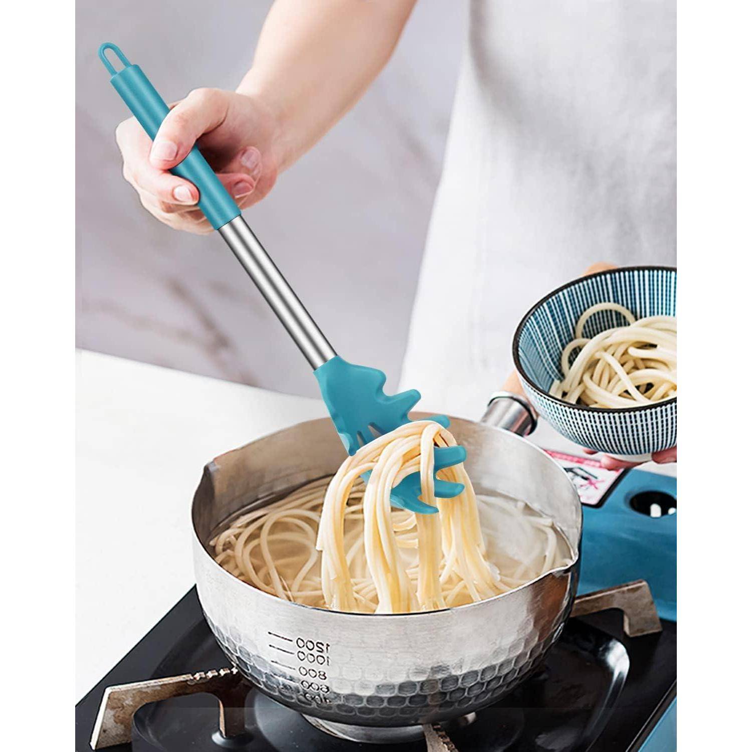 Eine Hand benutzt eine blaue Nudelgabel und schöpft gekochte Spaghetti aus einem Topf auf dem Herd, wobei eine danebenstehende Schüssel mit Nudeln auf der Arbeitsplatte steht.